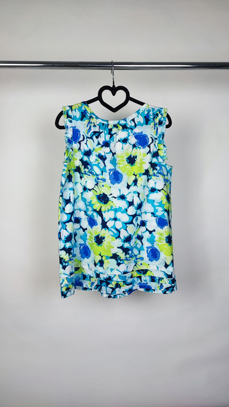 تصویر نیمقد زنی با تاپ بدونآستین طرحدار آبی‑سبز با زمینه روشن، در پسزمینه سفید.»