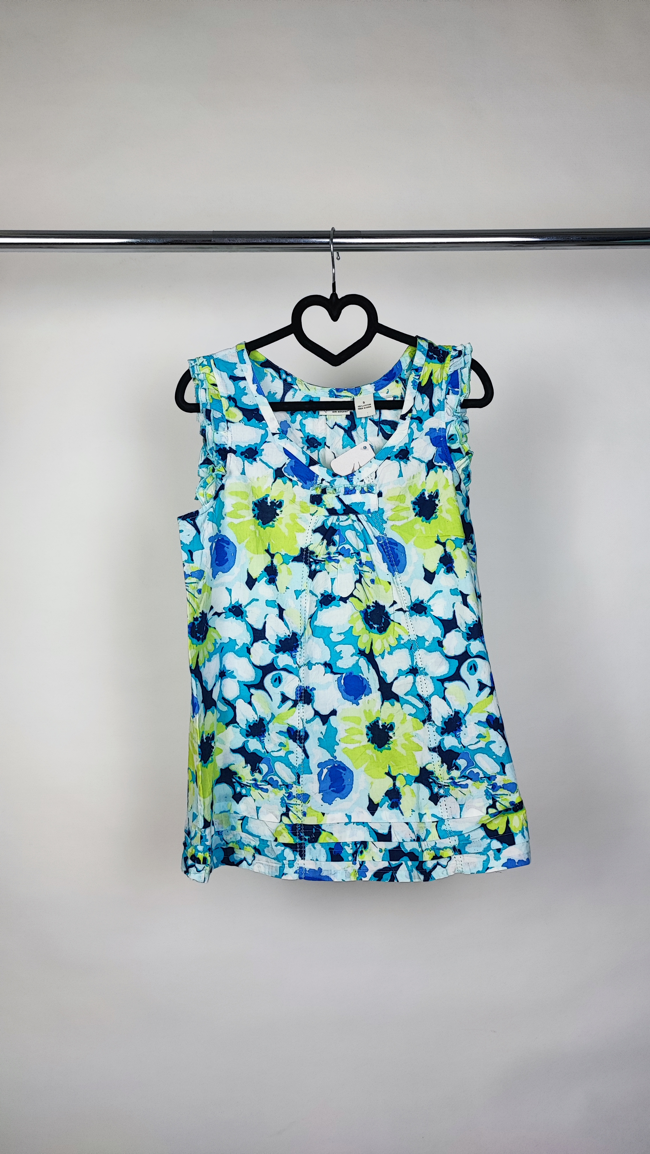 تصویر نیم‌قد زنی با تاپ بدون‌آستین طرح‌دار آبی‑سبز با زمینه روشن، در پس‌زمینه سفید.»