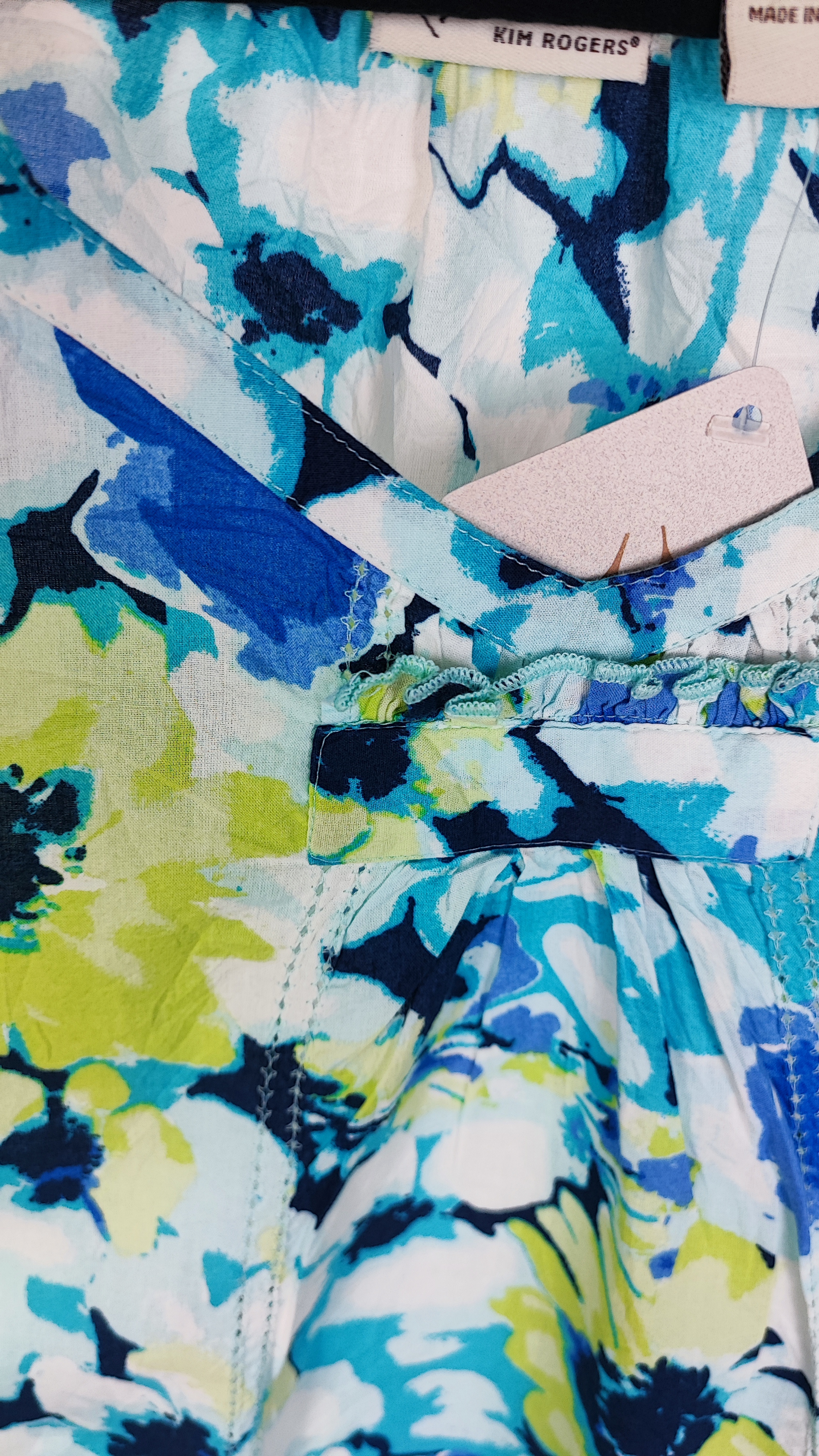 تصویر نیم‌قد زنی با تاپ بدون‌آستین طرح‌دار آبی‑سبز با زمینه روشن، در پس‌زمینه سفید.»