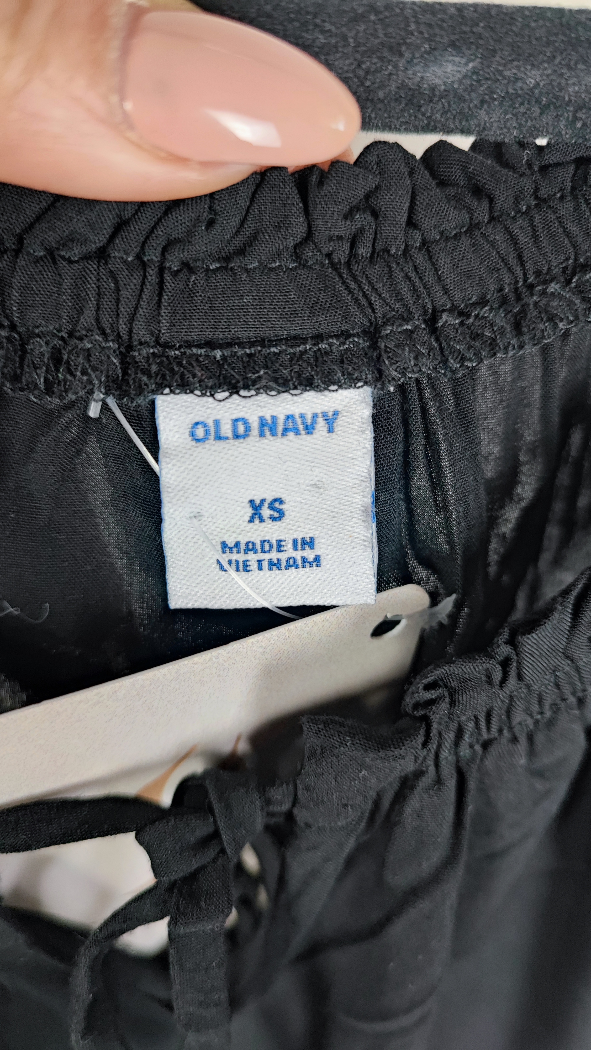 تصویر نیم‌تنه یک زن که شومیز مشکی آستین‌کوتاه پوشیده است. یقه گرد با نواردار دارد و جلوی لباس یک چین عمودی دیده می‌شود. پس‌زمینه ساده و روشن است.»