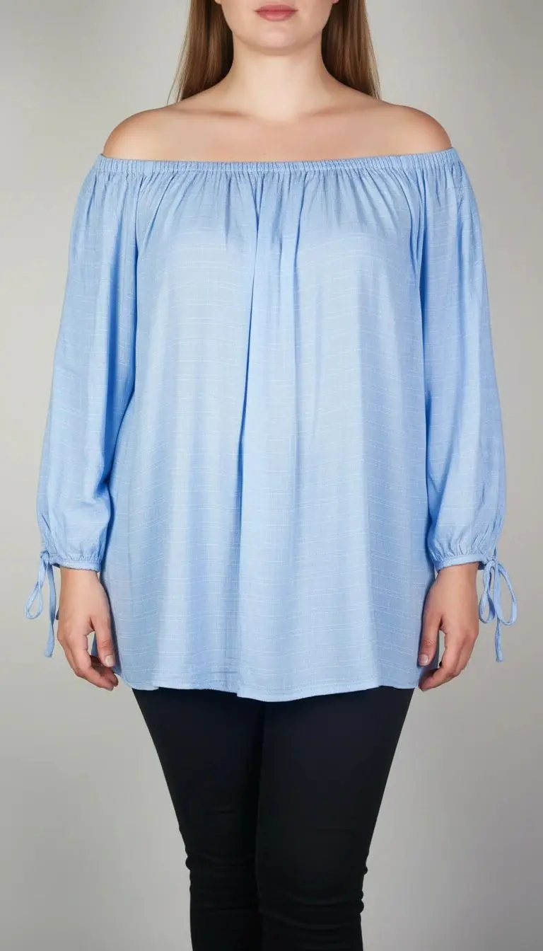 تصویر نیم‌تنه زنی که شومیز آبی روشن یقه‌کش و شانه‌باز با آستین بلند پوشیده است. فرم لباس آزاد است و پس‌زمینه روشن و ساده است.»