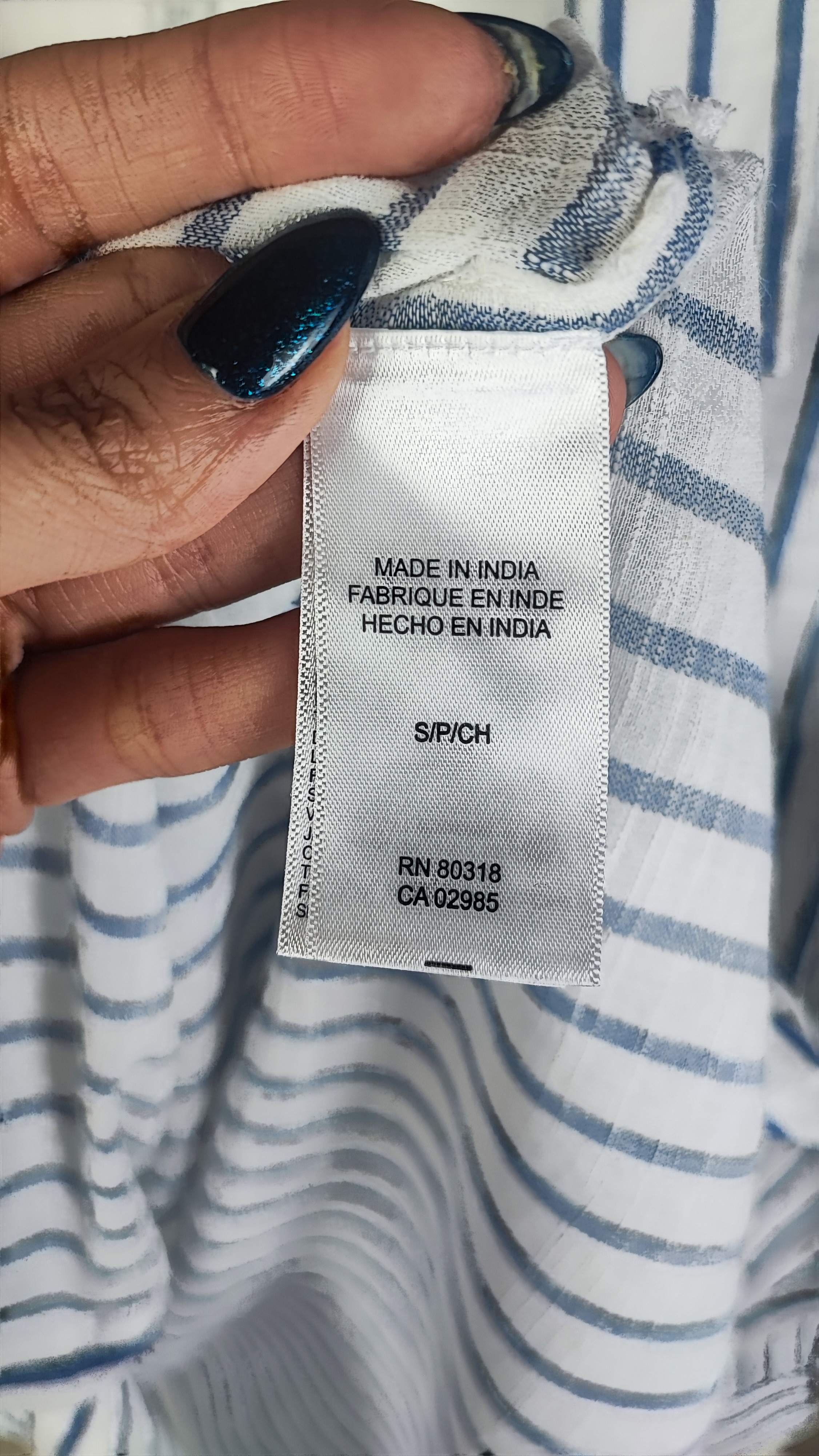 تصویر نیم‌تنه زنی با شومیز آستین‌بلند راه‌راه عمودی آبی و سفید، با یقه‌دار و فرم نیمه‌راسته. پس‌زمینه روشن و ساده است.»