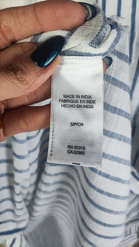 تصویر نیمتنه زنی با شومیز آستینبلند راهراه عمودی آبی و سفید، با یقهدار و فرم نیمهراسته. پسزمینه روشن و ساده است.»