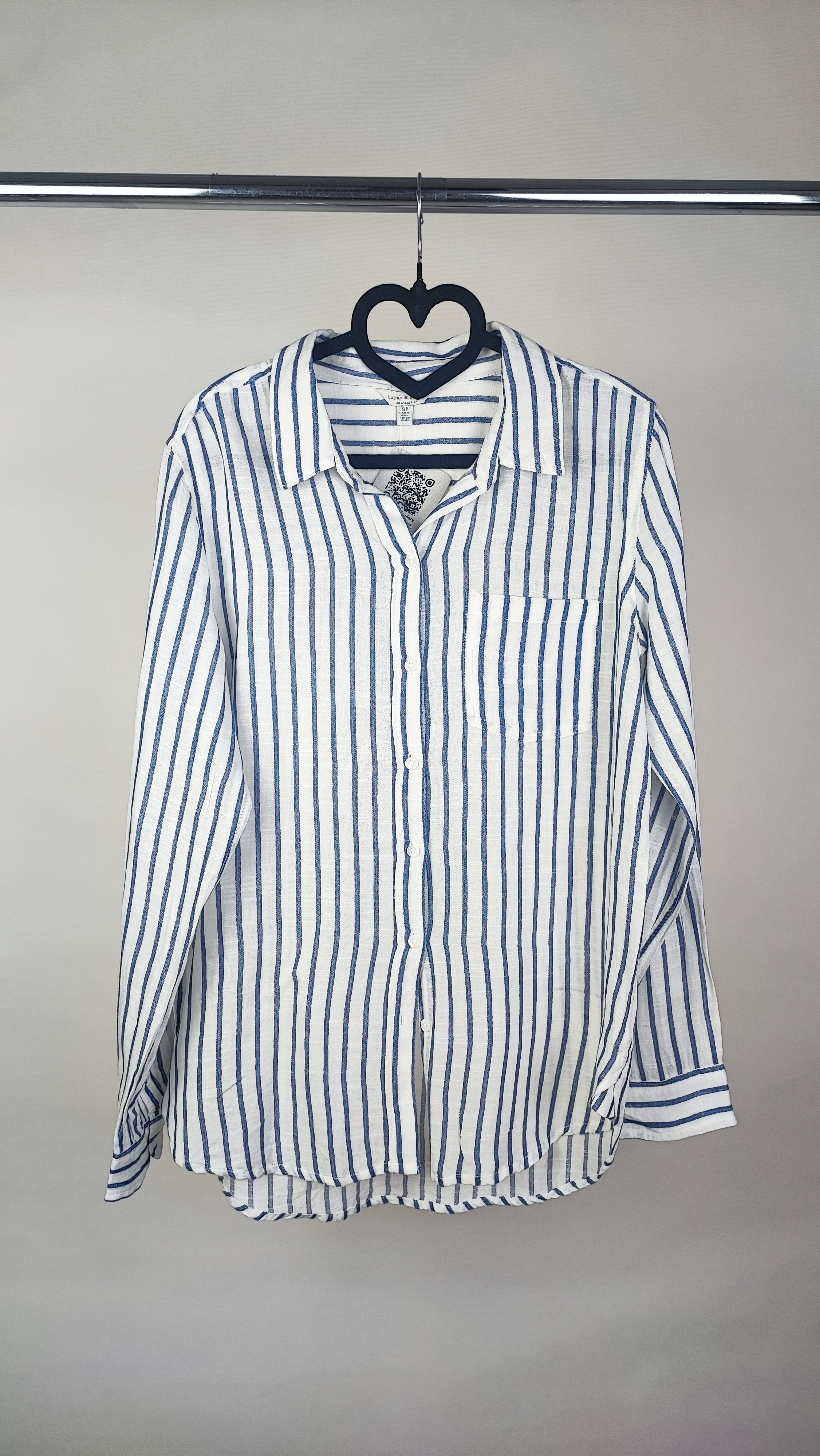 تصویر نیم‌تنه زنی با شومیز آستین‌بلند راه‌راه عمودی آبی و سفید، با یقه‌دار و فرم نیمه‌راسته. پس‌زمینه روشن و ساده است.»