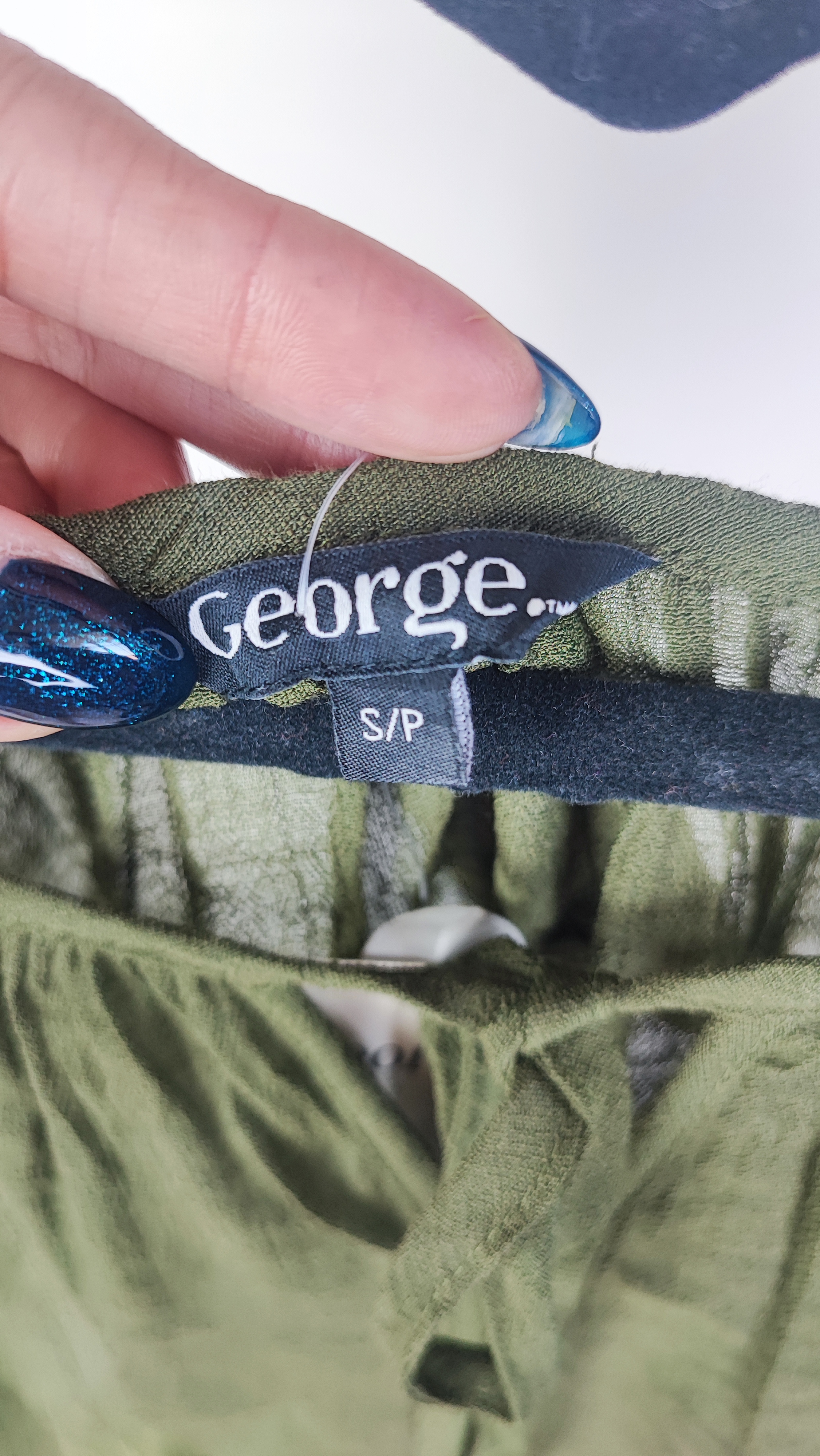 تصویر تمام‌قد زنی با شومیز سبز تیره آستین‌کوتاه و فرم آزاد که با شلوار جین تیره ست شده است. یقه گرد و پارچه سبک دارد