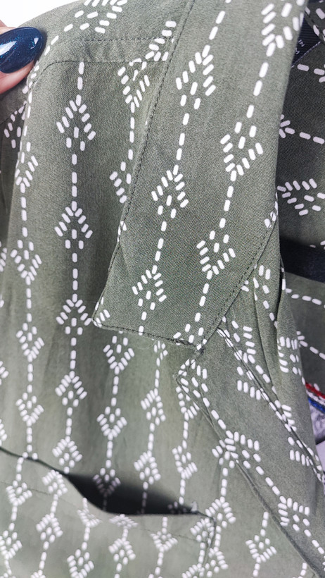 تصویر تمامقد زنی با شومیز سبز یشمی با یقه هفت و آستین کوتاه، ستشده با شلوار جین تیره. پسزمینه سفید و ساده است.»