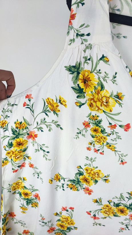 تصویر تمامقد زنی با تاپ بدونآستین روشنِ طرحدار با یقه هفت، ستشده با شلوار جین تیره. پسزمینه سفید و ساده است