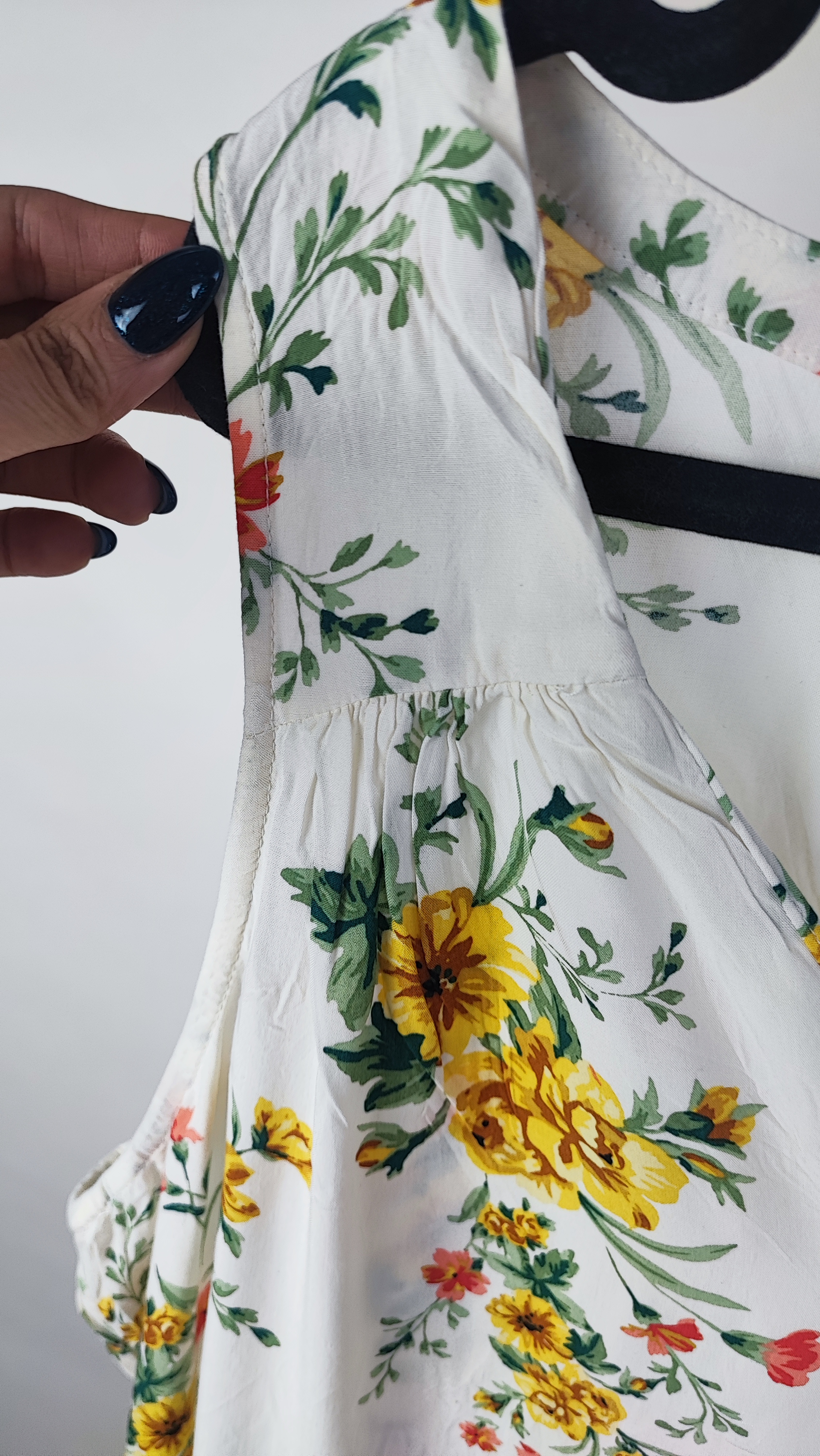 تصویر تمام‌قد زنی با تاپ بدون‌آستین روشنِ طرح‌دار با یقه هفت، ست‌شده با شلوار جین تیره. پس‌زمینه سفید و ساده است