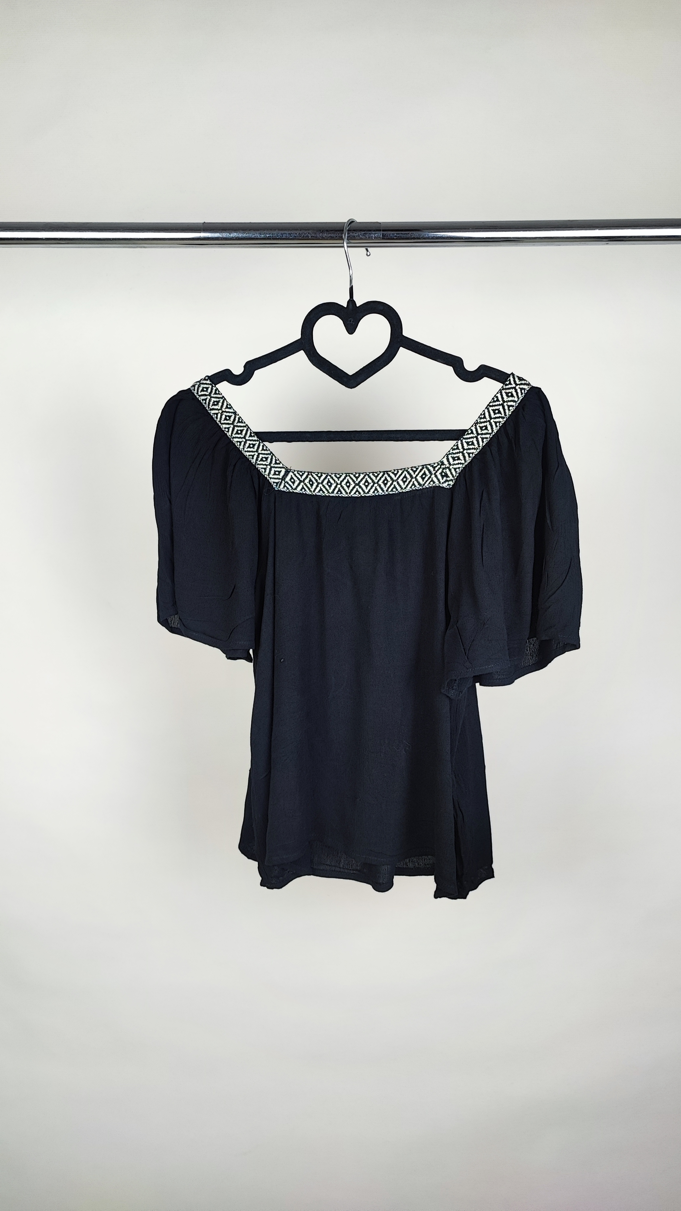 تصویر نیم‌قد زنی با شومیز مشکی مجلسی یقه‌لمه‌دار و آستین کوتاه فون، در پس‌زمینه سفید