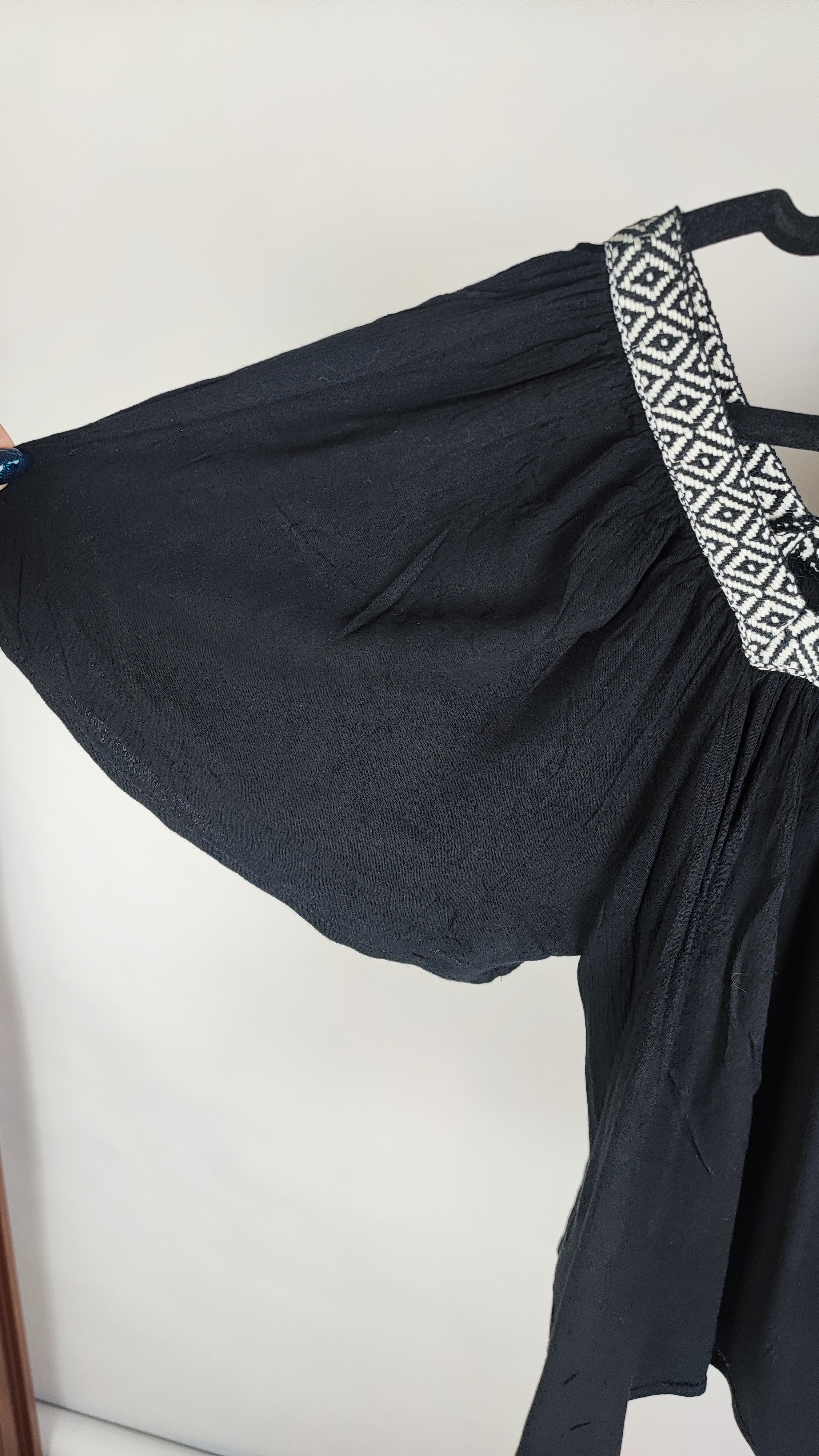 تصویر نیم‌قد زنی با شومیز مشکی مجلسی یقه‌لمه‌دار و آستین کوتاه فون، در پس‌زمینه سفید