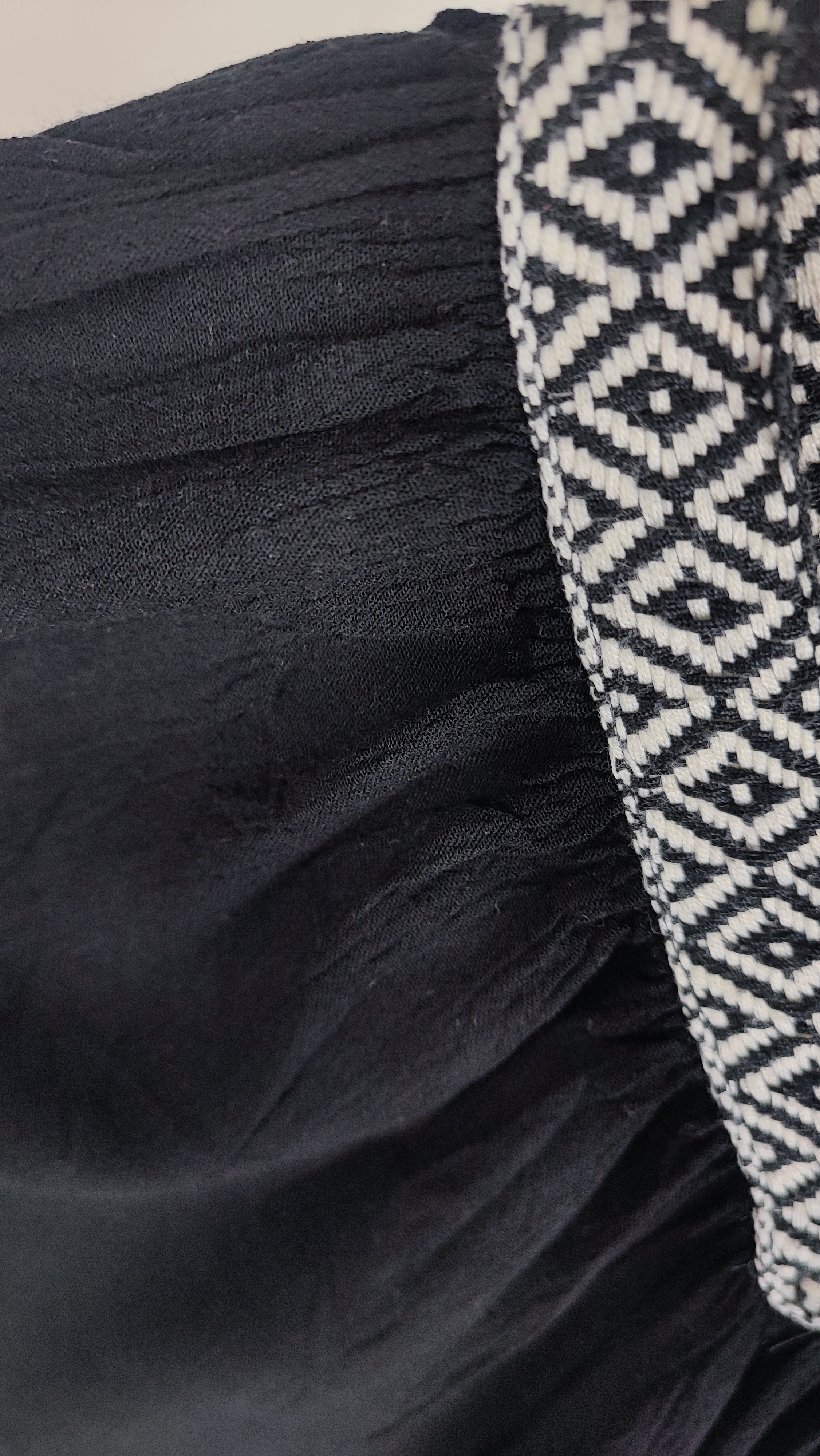 تصویر نیم‌قد زنی با شومیز مشکی مجلسی یقه‌لمه‌دار و آستین کوتاه فون، در پس‌زمینه سفید