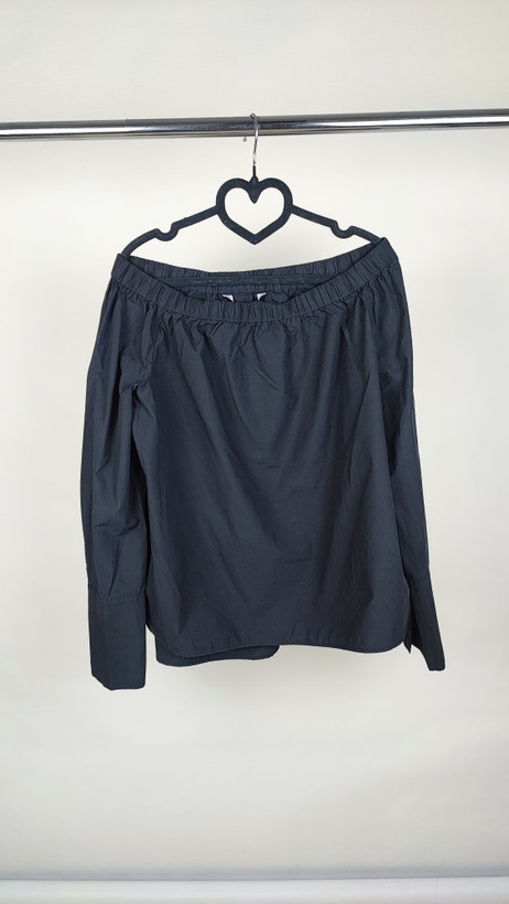 تصویر تمامقد زنی با شومیز مشکی آفشولدر (یقه باز روی شانه) و آستین بلند، ستشده با شلوار مشکی در پسزمینه سفید.»