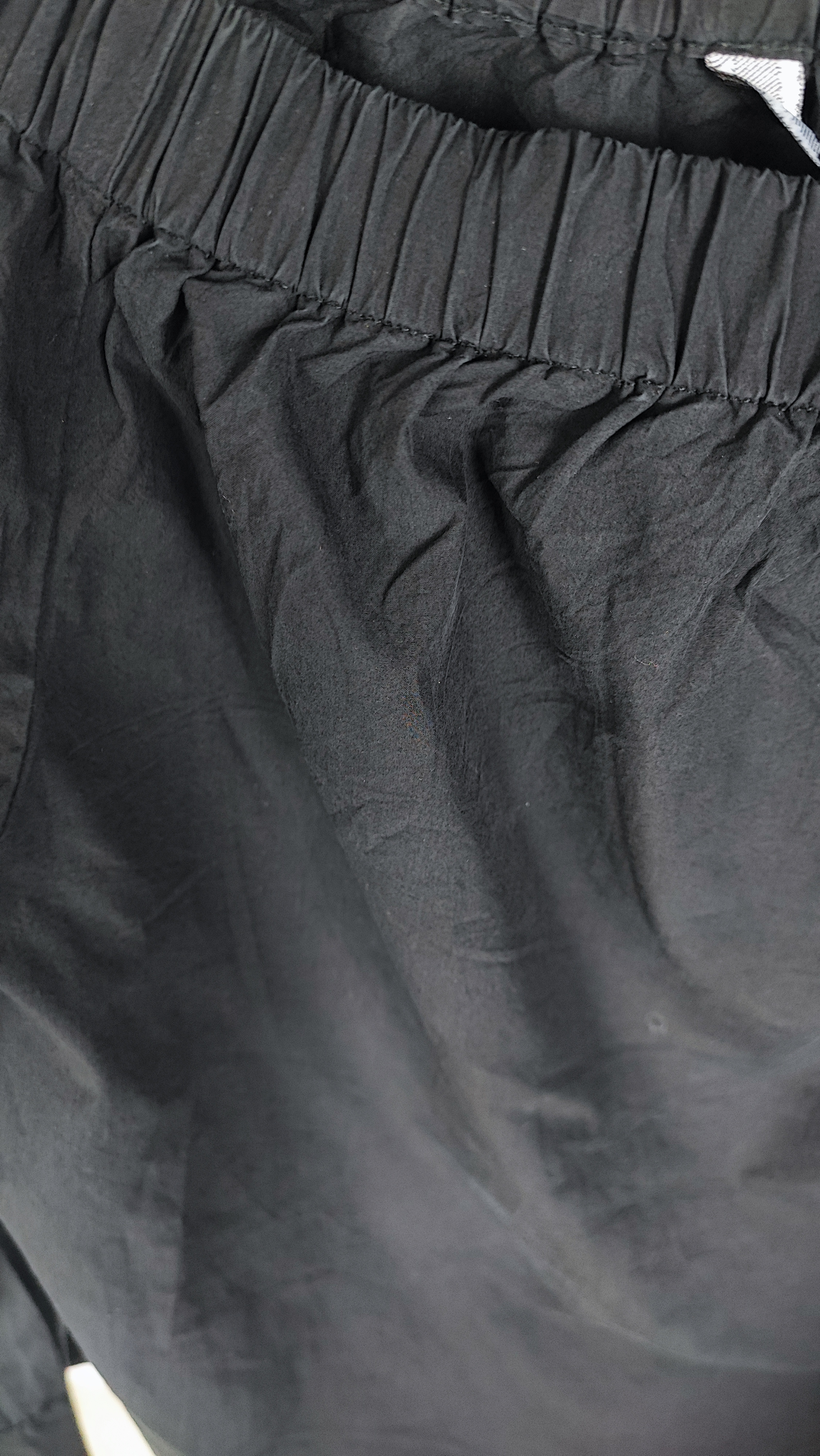 تصویر تمام‌قد زنی با شومیز مشکی آف‌شولدر (یقه باز روی شانه) و آستین بلند، ست‌شده با شلوار مشکی در پس‌زمینه سفید.»