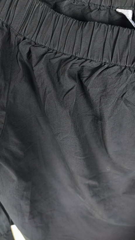 تصویر تمامقد زنی با شومیز مشکی آفشولدر (یقه باز روی شانه) و آستین بلند، ستشده با شلوار مشکی در پسزمینه سفید.»