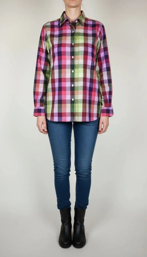 زن با شومیز چهارخونه آستینبلند در ترکیب رنگی صورتی، سبز و کرم دیده میشود. یقه برگردان و فرم لباس معمولی است و با شلوار جین تیره ست شده.»