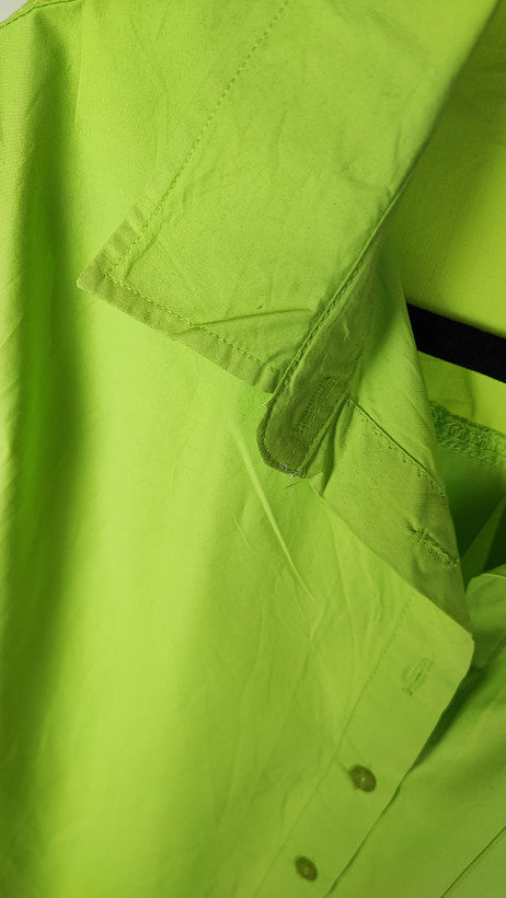 زن با شومیز لیمویی روشن آستینبلند و یقه برگردان دیده میشود. فرم لباس آزاد است و با شلوار جین تیره ست شده.»