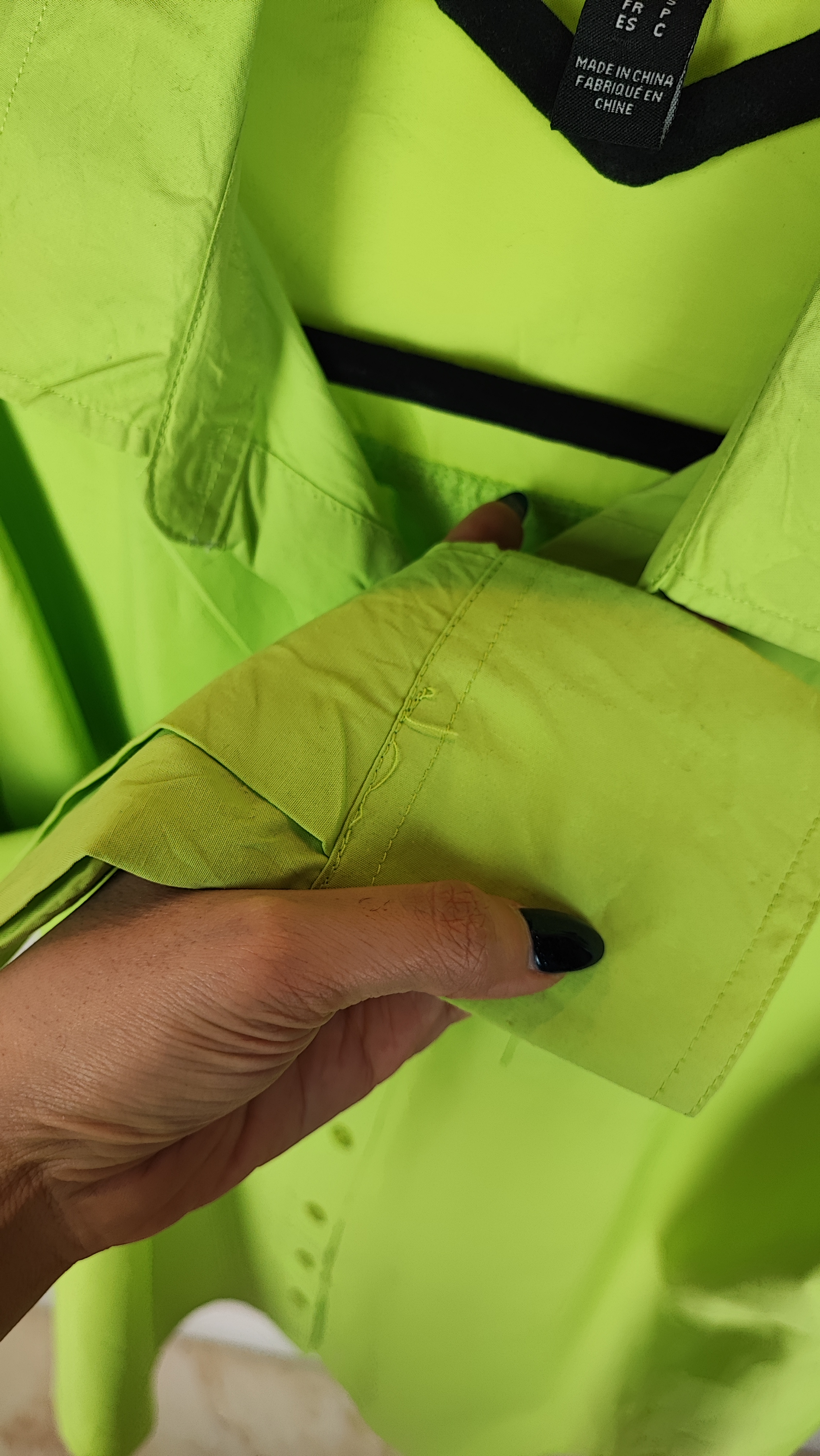 زن با شومیز لیمویی روشن آستین‌بلند و یقه برگردان دیده می‌شود. فرم لباس آزاد است و با شلوار جین تیره ست شده.»