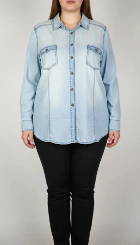 زن با شومیز جین آبی روشن سایز بزرگ و آستینبلند که جلو آن دکمهدار و دارای دو جیب سینه است، در پسزمینه روشن ایستاده.»
