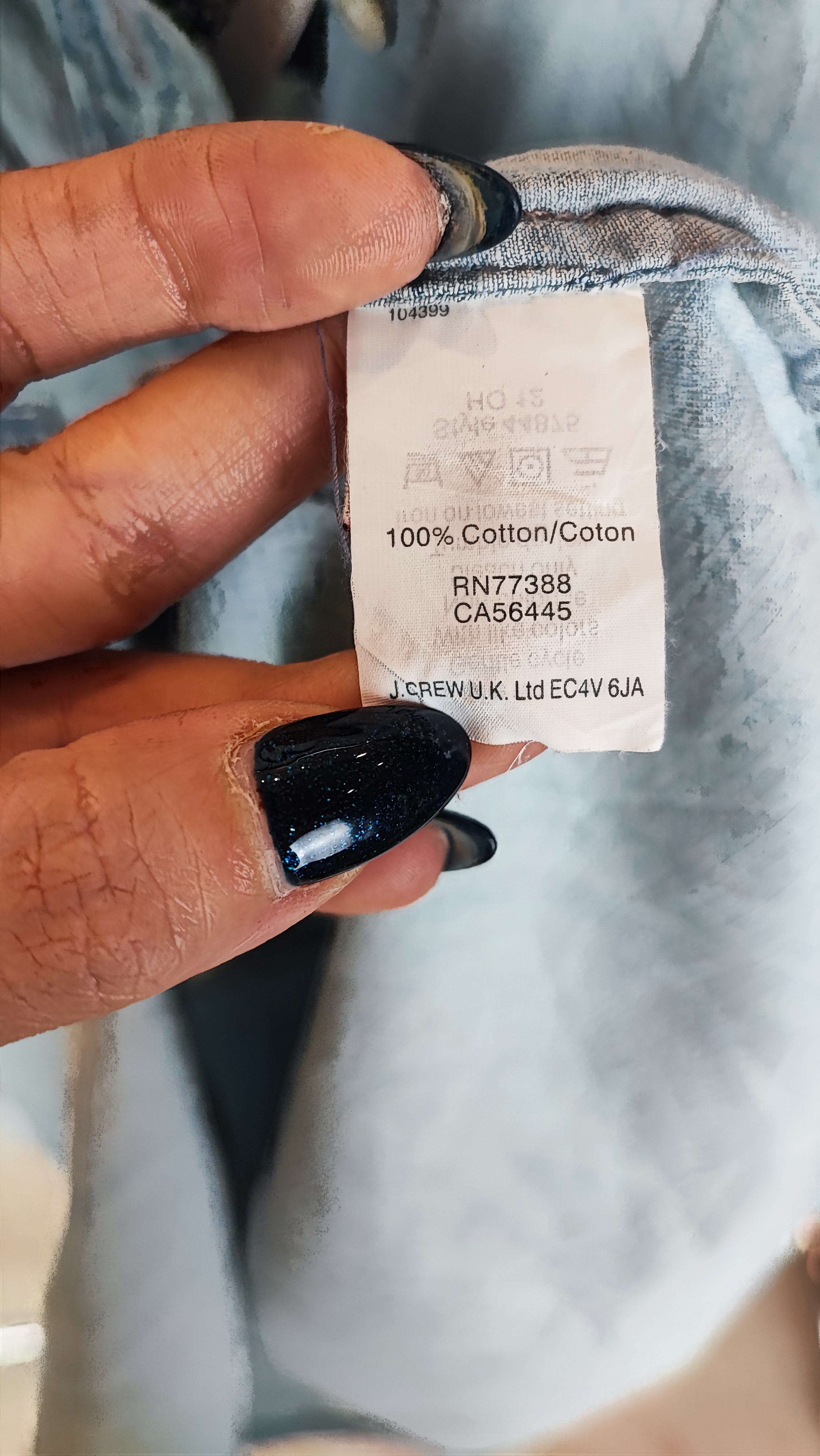 زن با شومیز جین آبی روشن دکمه‌دار و آستین‌بلند که تا آرنج رول شده و دارای دو جیب روی سینه است، در پس‌زمینه روشن ایستاده.»