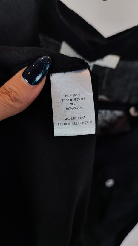 تاپ زنانه مشکی بدون آستین با دکمههای جلو و یقهبرگردان روی تن مدل در پسزمینه روشن.»