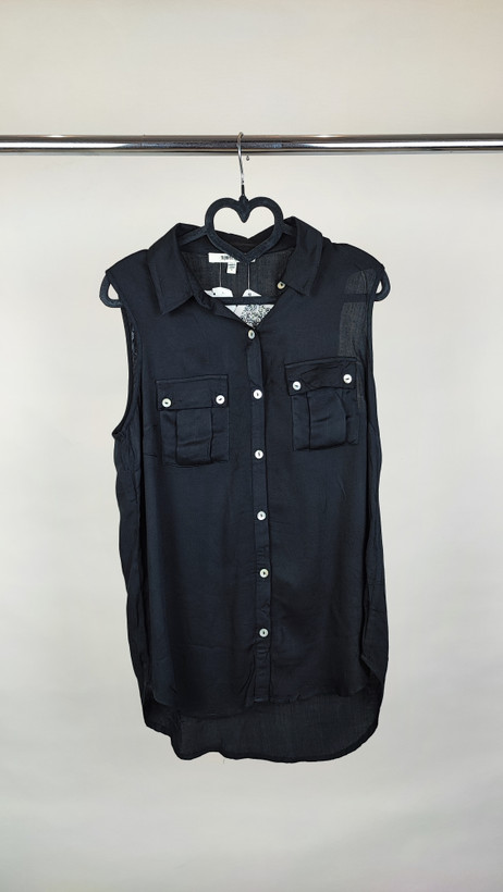 تاپ زنانه مشکی بدون آستین با دکمههای جلو و یقهبرگردان روی تن مدل در پسزمینه روشن.»