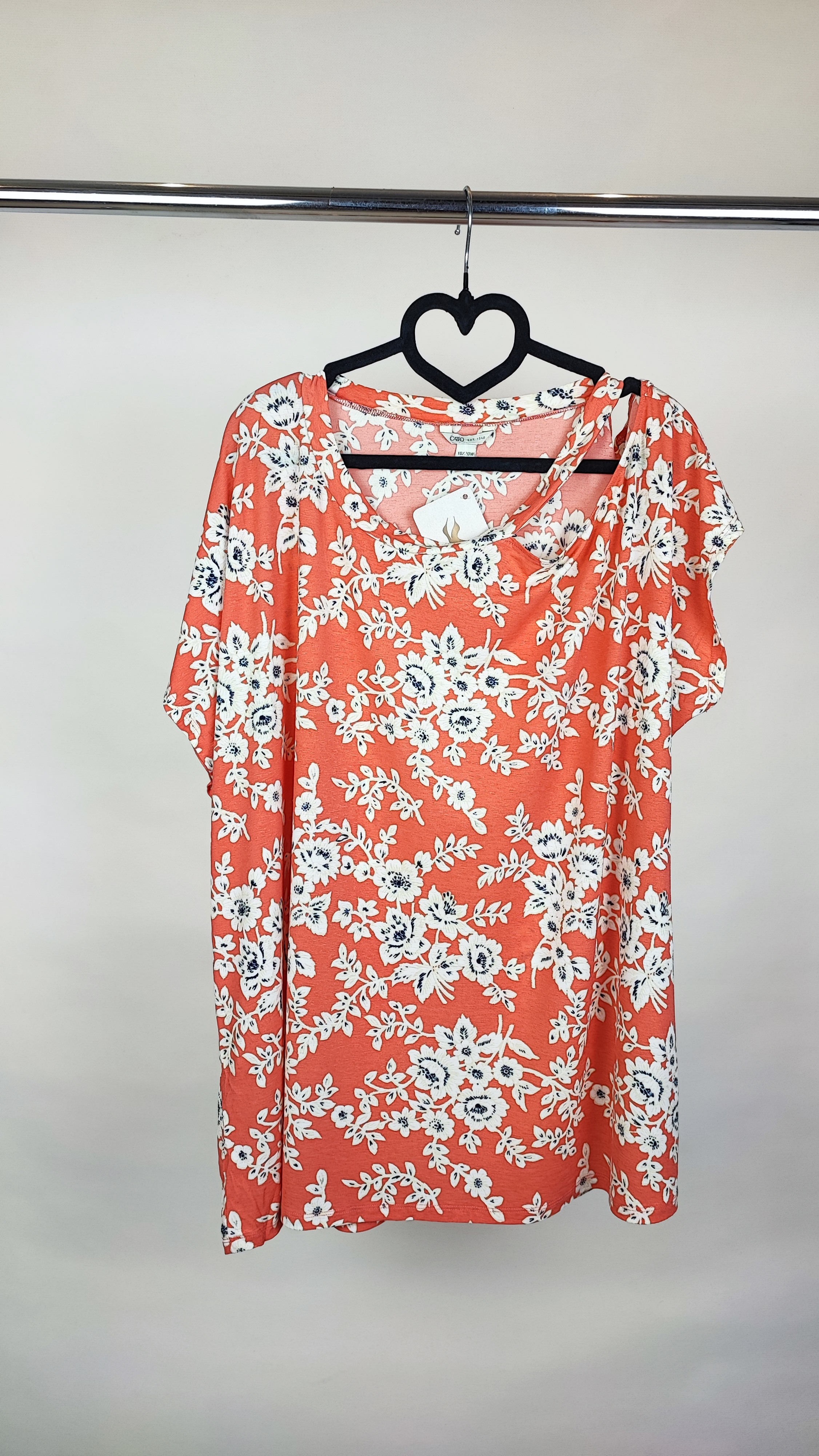 تیشرت زنانه سایز بزرگ با طرح رنگی نارنجی و کرم، آستین‌کوتاه و تن‌خور آزاد که روی شلوار جین پوشیده شده است.»