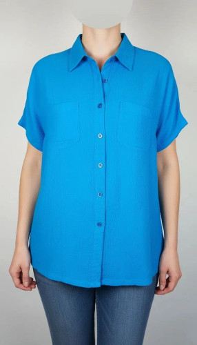 زن با شومیز آبی روشن آستینکوتاه و دکمهدار، دارای یقه برگردان، ایستاده در پسزمینه روشن