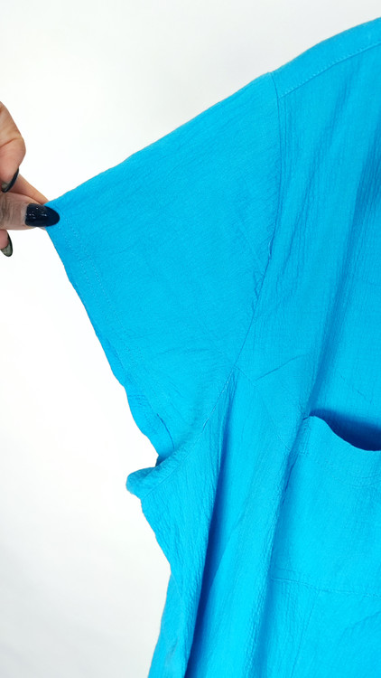 زن با شومیز آبی روشن آستینکوتاه و دکمهدار، دارای یقه برگردان، ایستاده در پسزمینه روشن