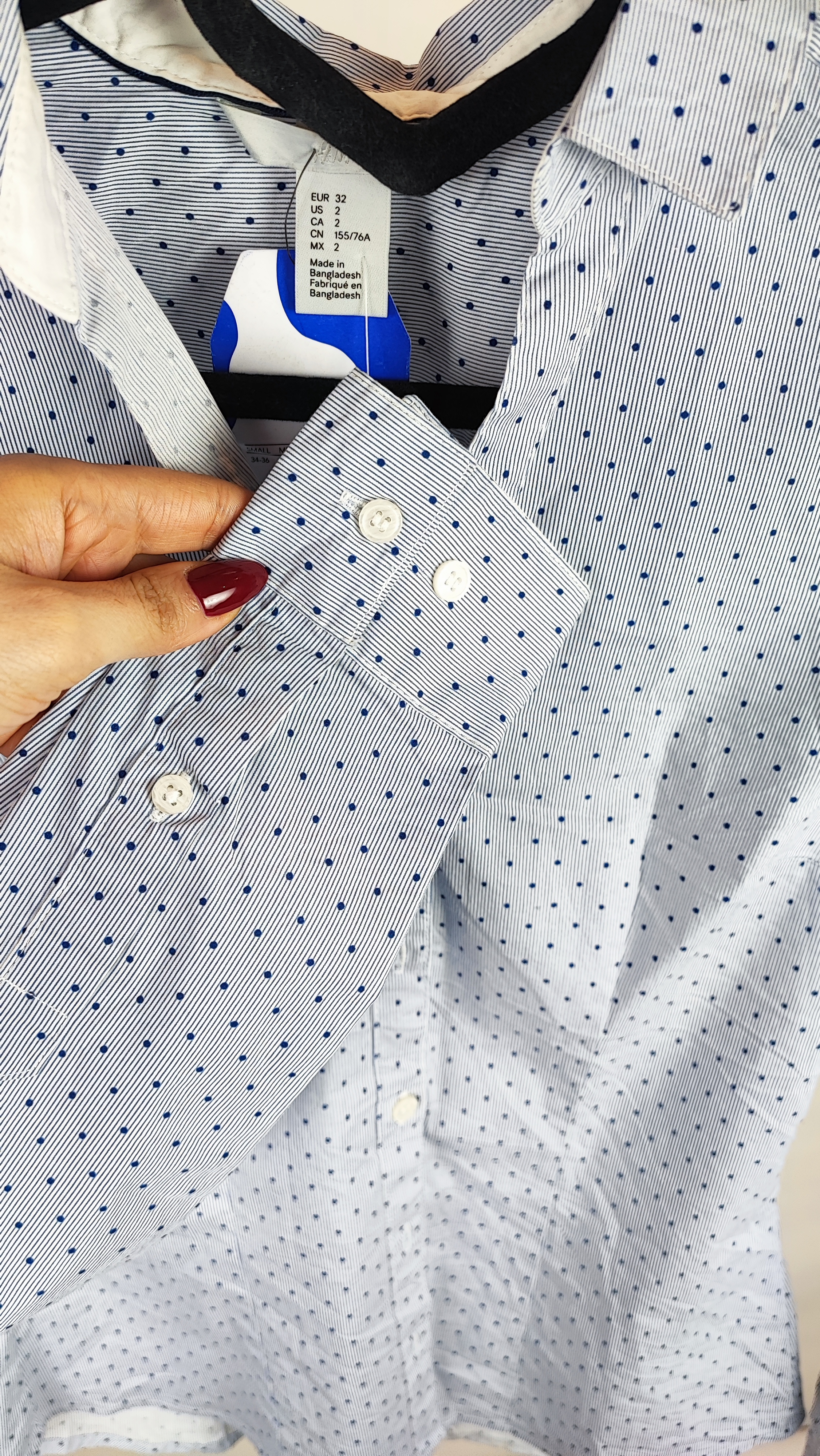 زن با شومیز آبیروشن دکمهدار و یقهبرگردان، آستینبلند و بدون طرح، در پسزمینه روشن ایستاده است