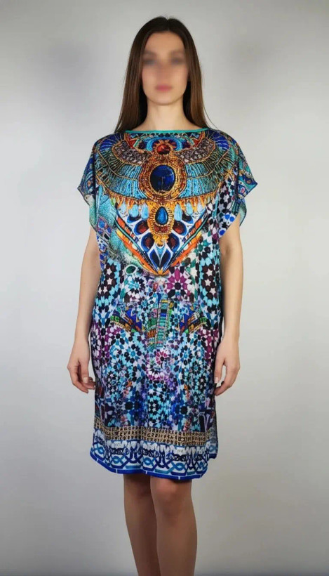 زن با پیراهن کوتاه طرحدار چندرنگ با آستین کوتاه و قد تا بالای زانو در پسزمینه روشن ایستاده است.»