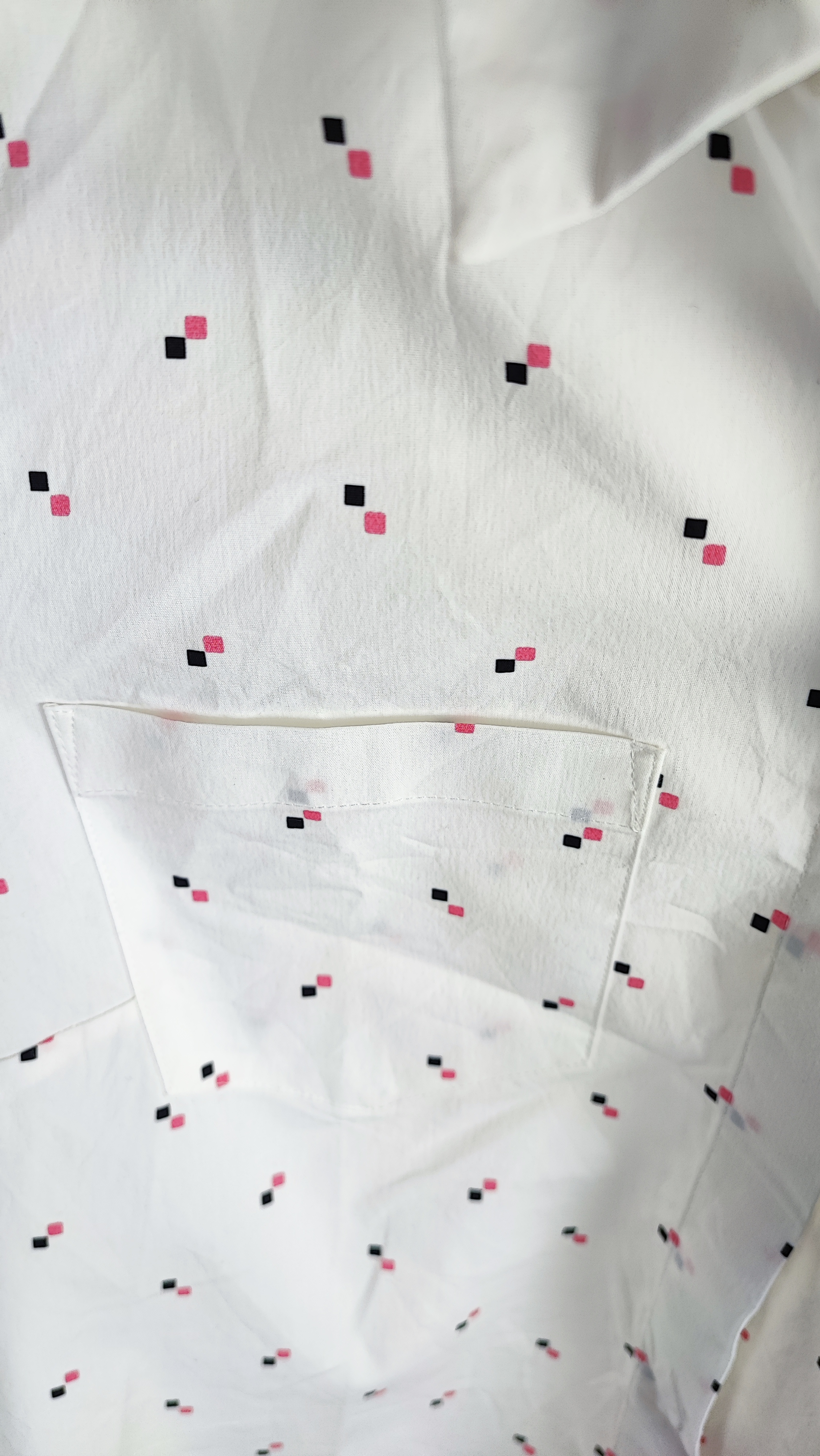 زن ایستاده با شومیز سفید آستین‌کوتاه و یقه‌دار، همراه با شلوار جین روشن در پس‌زمینه ساده.»