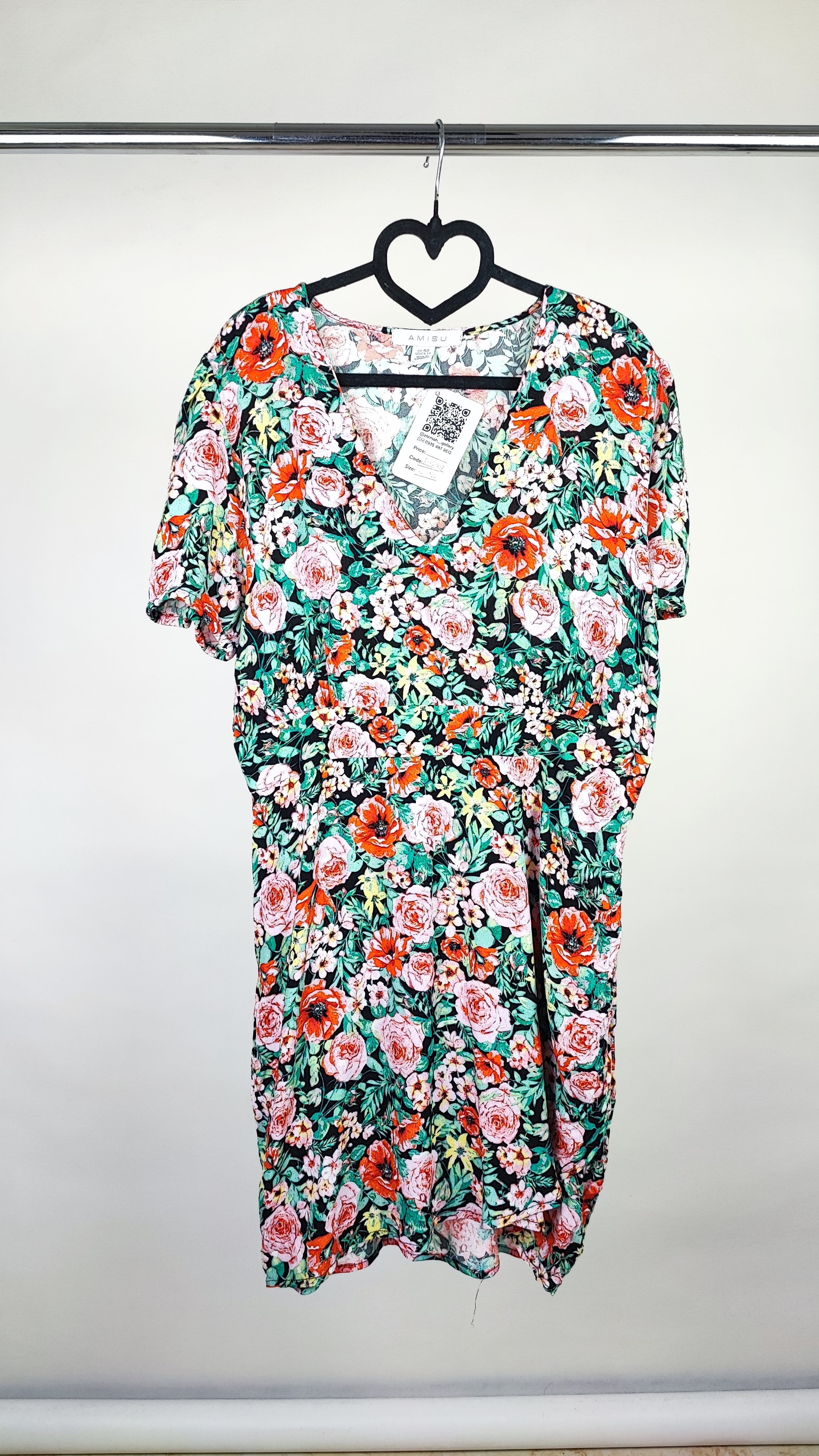 زن ایستاده با پیراهن کوتاه گل‌دار چندرنگ و یقه‌هفت، آستین‌کوتاه، در پس‌زمینه ساده.»