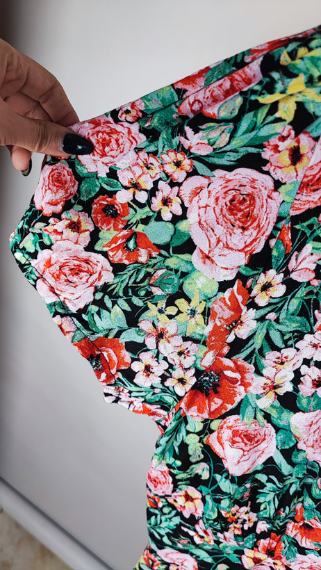 زن ایستاده با پیراهن کوتاه گلدار چندرنگ و یقههفت، آستینکوتاه، در پسزمینه ساده.»