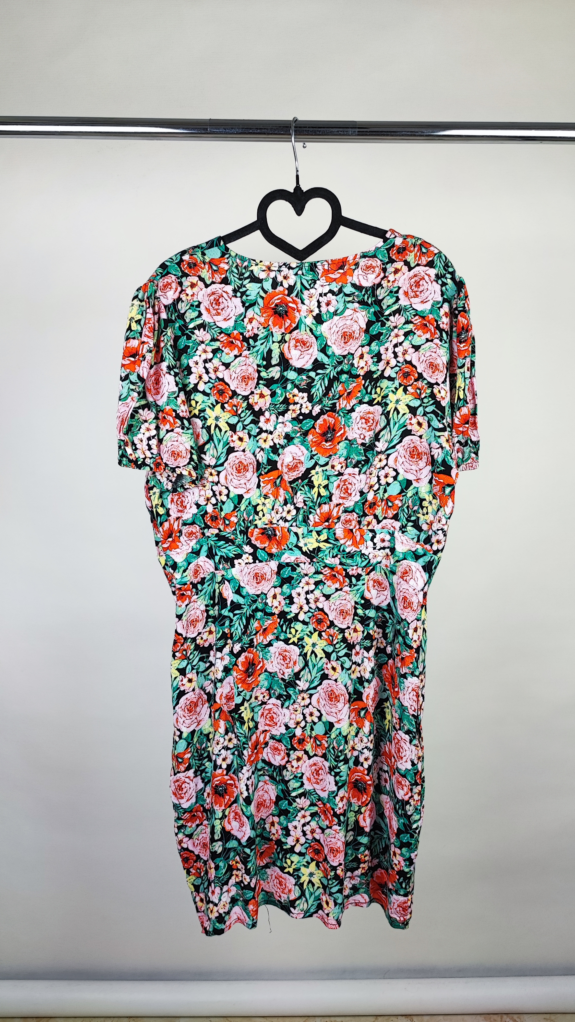 زن ایستاده با پیراهن کوتاه گل‌دار چندرنگ و یقه‌هفت، آستین‌کوتاه، در پس‌زمینه ساده.»