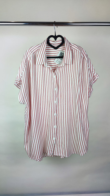 زن سایزبزرگ با شومیز راهراه روشن آستینکوتاه و یقهدار در پسزمینه ساده.»