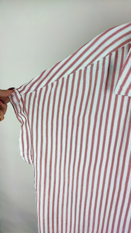 زن سایزبزرگ با شومیز راهراه روشن آستینکوتاه و یقهدار در پسزمینه ساده.»