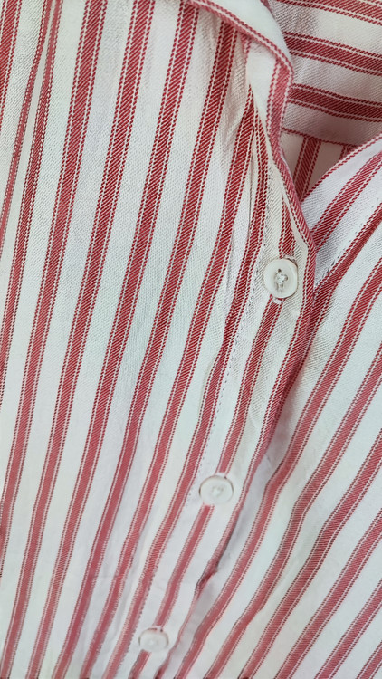 زن سایزبزرگ با شومیز راهراه روشن آستینکوتاه و یقهدار در پسزمینه ساده.»