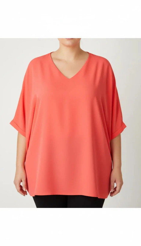 زن سایزبزرگ با شومیز آزاد یقههفت کوتاهآستین به رنگ گلبهی در پسزمینه ساده.»