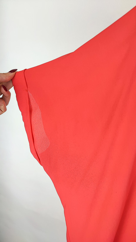 زن سایزبزرگ با شومیز آزاد یقههفت کوتاهآستین به رنگ گلبهی در پسزمینه ساده.»