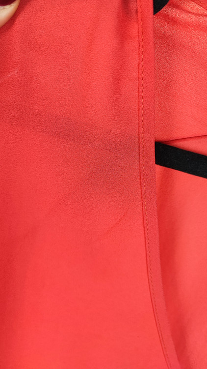 زن سایزبزرگ با شومیز آزاد یقههفت کوتاهآستین به رنگ گلبهی در پسزمینه ساده.»