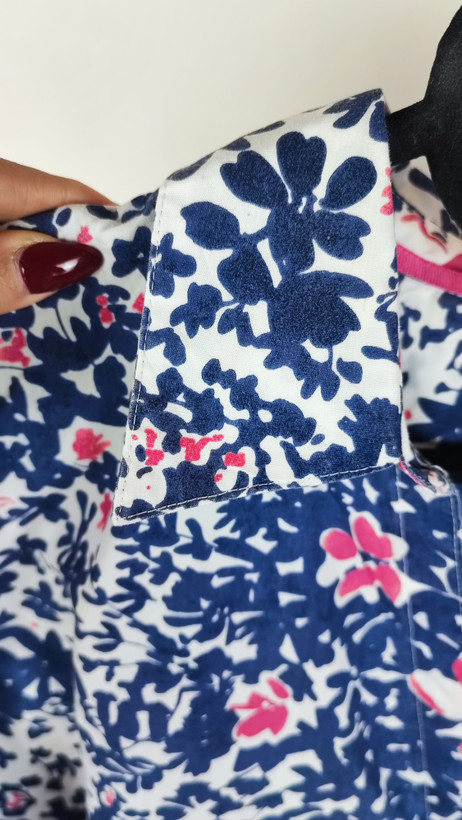 زن سایزبزرگ با تاپ بدونآستین آبی طرحدار و شلوار جین در پسزمینه ساده.»