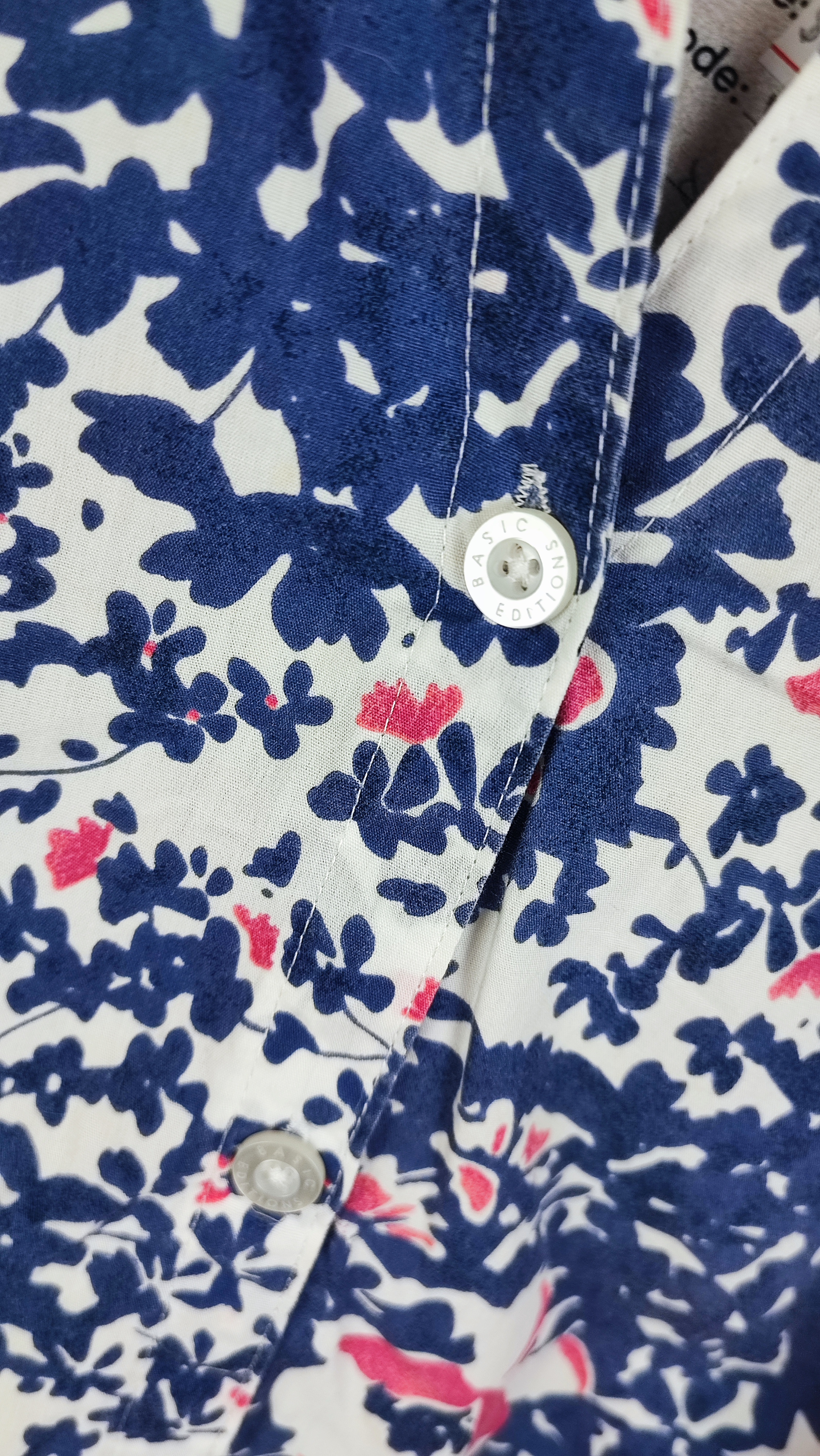 زن سایزبزرگ با تاپ بدون‌آستین آبی طرح‌دار و شلوار جین در پس‌زمینه ساده.»