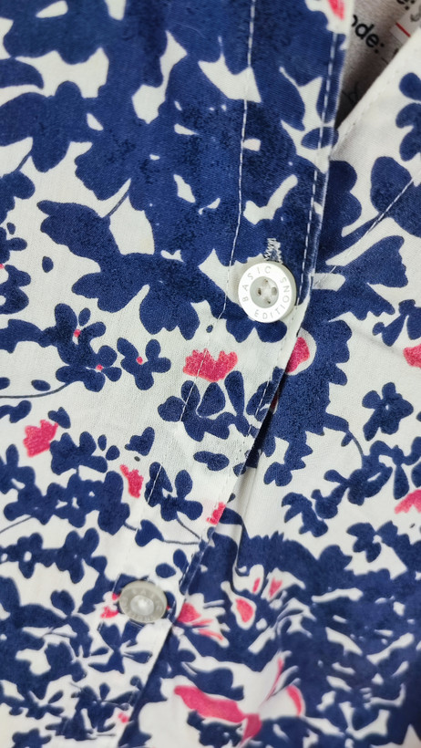 زن سایزبزرگ با تاپ بدونآستین آبی طرحدار و شلوار جین در پسزمینه ساده.»