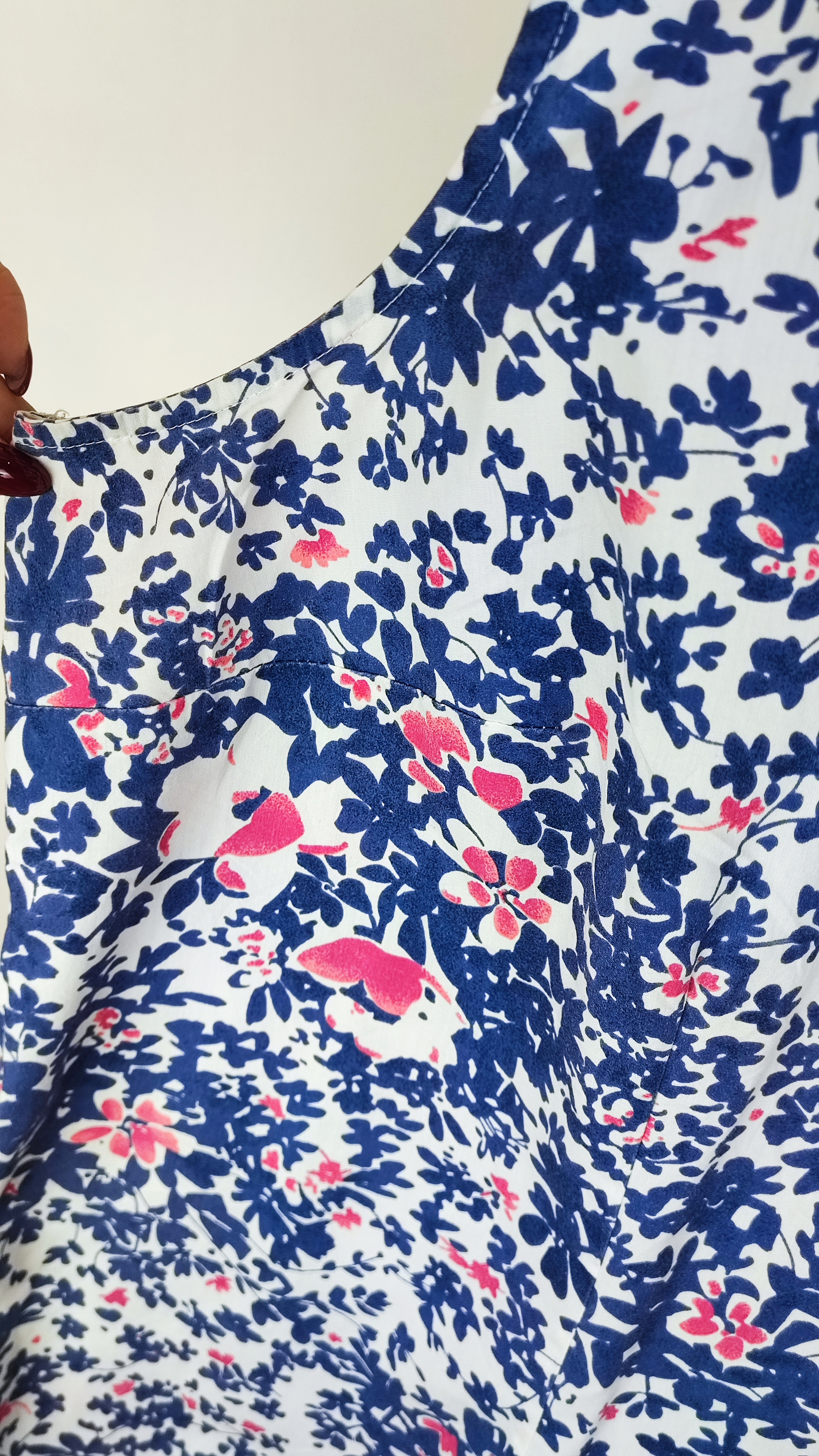 زن سایزبزرگ با تاپ بدون‌آستین آبی طرح‌دار و شلوار جین در پس‌زمینه ساده.»