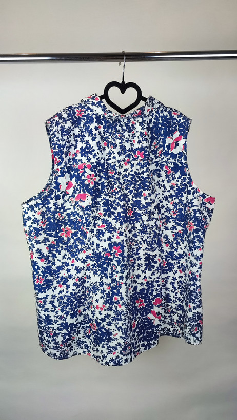 زن سایزبزرگ با تاپ بدونآستین آبی طرحدار و شلوار جین در پسزمینه ساده.»