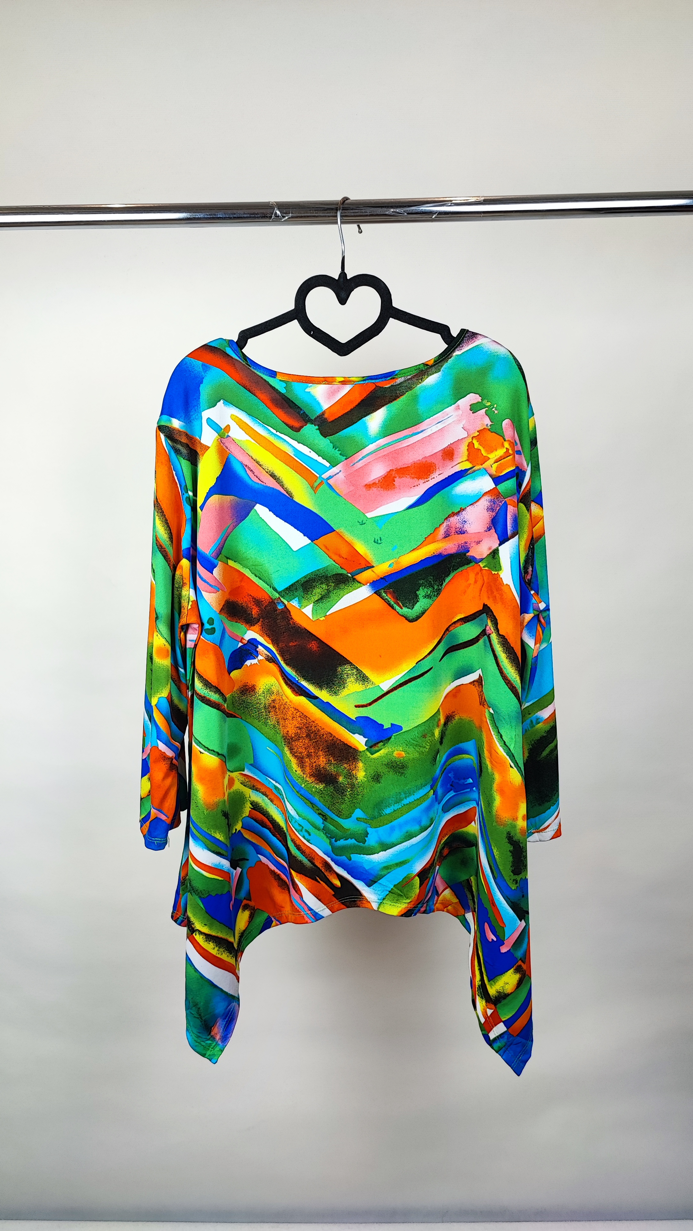 بلوز زنانه سایز بزرگ با طرح رنگارنگ آبی، نارنجی و سبز، آستین‌بلند، روی تن مانکن با شلوار جین تیره در پس‌زمینه روشن.»