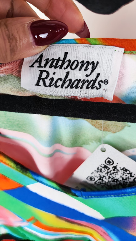 بلوز زنانه سایز بزرگ با طرح رنگارنگ آبی، نارنجی و سبز، آستینبلند، روی تن مانکن با شلوار جین تیره در پسزمینه روشن.»