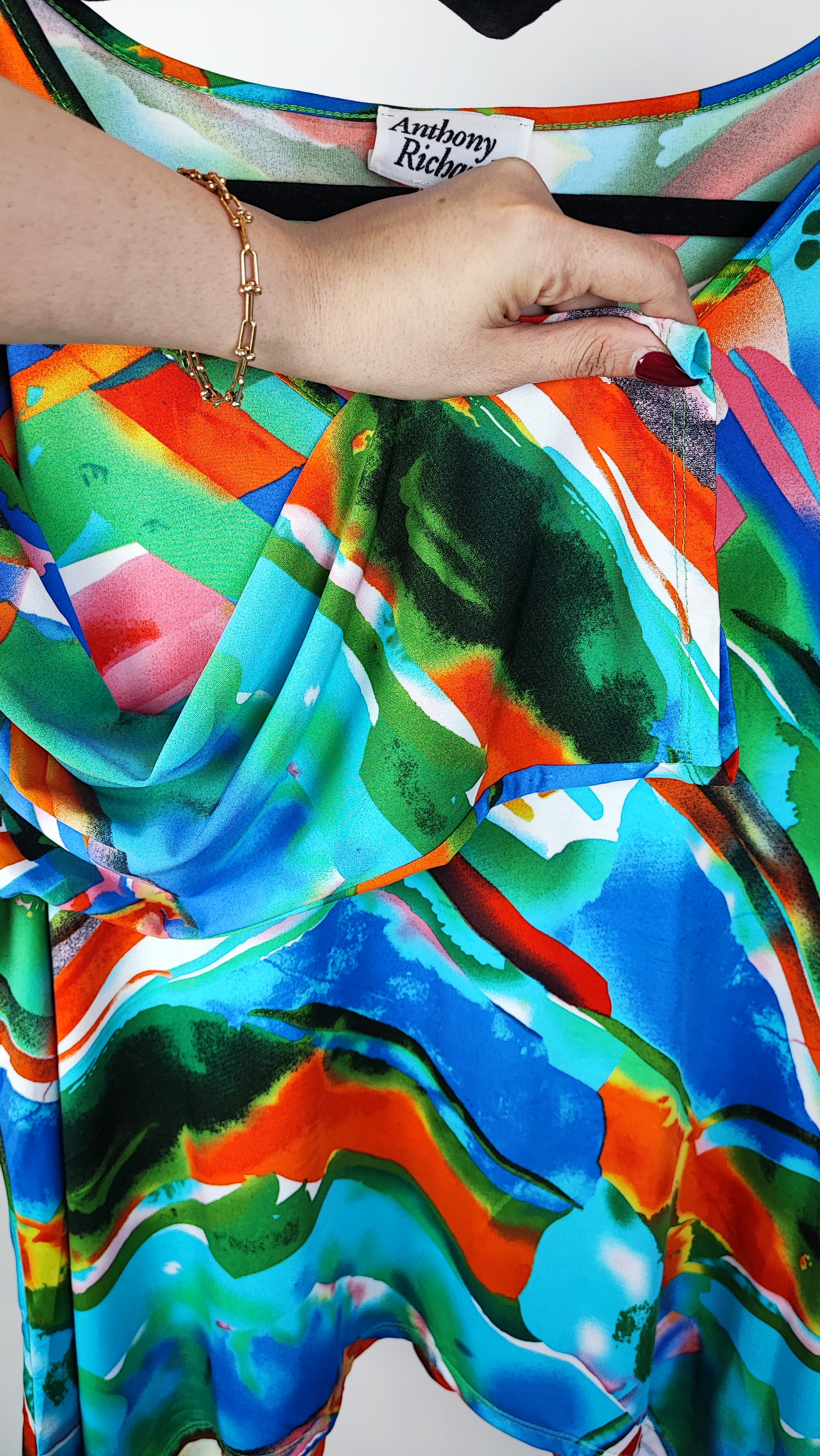 بلوز زنانه سایز بزرگ با طرح رنگارنگ آبی، نارنجی و سبز، آستین‌بلند، روی تن مانکن با شلوار جین تیره در پس‌زمینه روشن.»