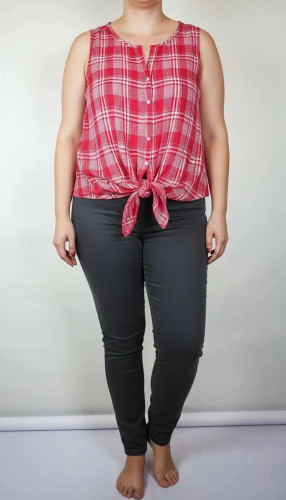 تاپ زنانه سایز بزرگ چهارخونه صورتی و قرمز، بدون آستین با گره جلو، روی تن مانکن با شلوار تیره در پسزمینه روشن.»