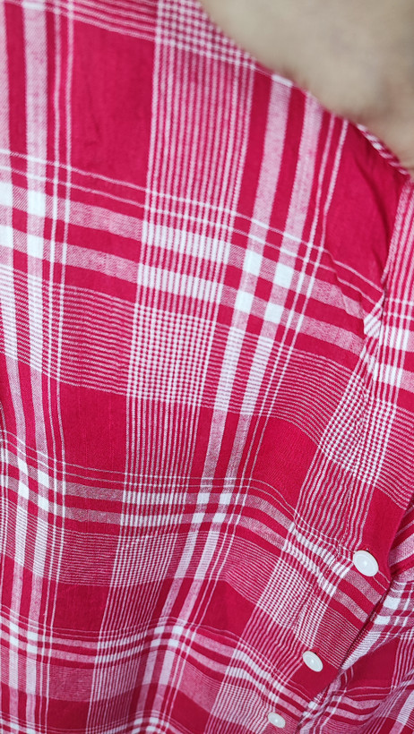 تاپ زنانه سایز بزرگ چهارخونه صورتی و قرمز، بدون آستین با گره جلو، روی تن مانکن با شلوار تیره در پسزمینه روشن.»